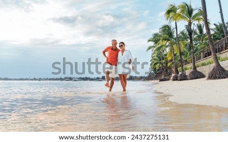 Couple in love hugging while walking on a sandy exotic beach. They have an evening walk by Trou-aux-Biches seashore on Mauritius island. People relationship and tropic honeymoon vacations concept