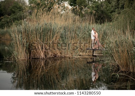 Couple in love hugs and kissing at wooden pier at nature