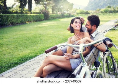 Couple in love joking together on a bench with bikes on vacation