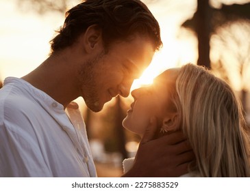 Couple, love and kiss outdoor at sunset for love, care and romance with hands on face on a date. Young man and woman together on valentines day with lens flare, peace and freedom in nature forest