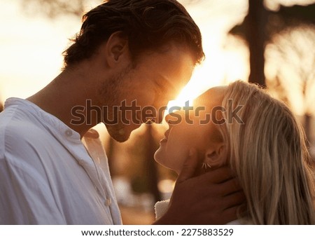 Couple, love and kiss outdoor at sunset for love, care and romance with hands on face on a date. Young man and woman together on valentines day with lens flare, peace and freedom in nature forest