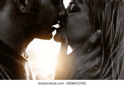 Couple in love kissing on sunset - Boyfriend and girlfriend hugging outdoor - Two lovers having romantic date - Black and white filter - Love background concept