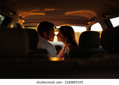 Couple in love kissing sitting in the car at sunset