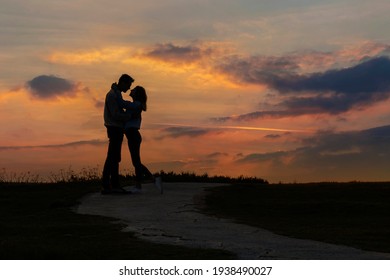 Couple In Love Kissing At Sunset. Silhouette Of Two People On A Background Of Beautiful Evening Sky.