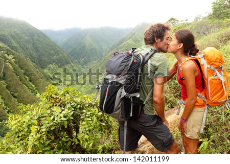 Couple in love kissing while hiking on Hawaii. Romantic young couple hikers during hike in beautiful mountain forest nature. Healthy lifestyle multi-ethnic couple on Waihee ridge trail, Maui, USA