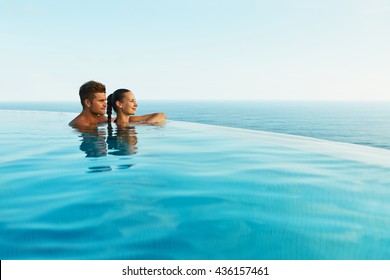 Couple In Love At Luxury Resort On Romantic Summer Vacation. People Relaxing Together In Edge Swimming Pool Water, Enjoying Beautiful Sea View. Happy Lovers On Honeymoon Travel. Relationship, Romance - Powered by Shutterstock