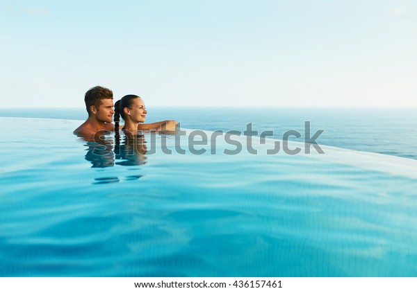 ロマンチックな夏休みの高級リゾートで恋をしているカップル 人々は縁のプールの水でくつろぎ 美しい海を楽しみます 新婚旅行で幸せな恋人 恋愛関係 の写真素材 今すぐ編集