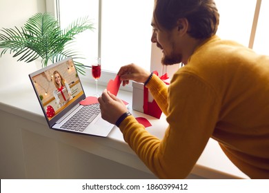 Couple in love miss each other in lockdown and look forward to meeting in person. Happy young man showing his girlfriend red heart card on romantic virtual date via video call on Saint Valentine's Day - Powered by Shutterstock