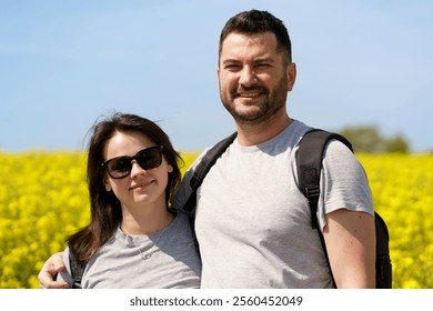 Couple in love on the background of a blooming rapeseed field. Active backpacking travel concept - Powered by Shutterstock