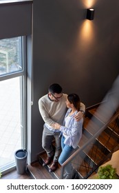 Couple In Love On A Date, Looking At Each Other, Hugging, Holding Hands And Walking Down The Restaurant Stairs