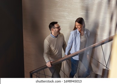 Couple In Love On A Date In A Restaurant, Looking At Each Other, Holding Hands And Walking Up The Stairs