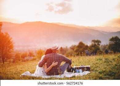 couple in love on a white plaid in a field on a picnic. against a background of a sunset in the mountains. romance - Powered by Shutterstock