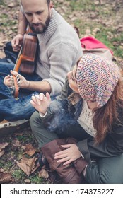 couple in love playing serenade with guitar at the park winter