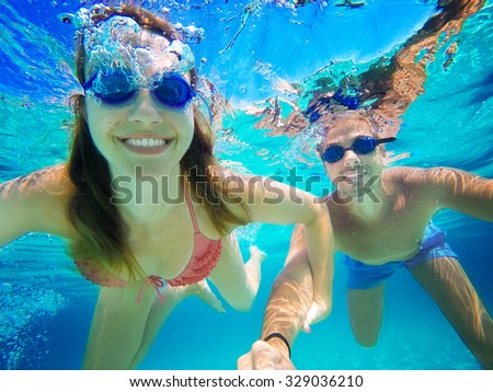 Couple in love refreshing underwater on vacation. Diving. Wide angle selfie shot.