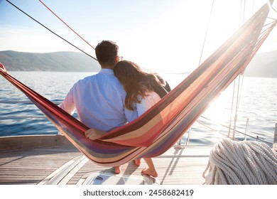 Couple in love relaxing in beach hammock on yacht at sea. Man and woman traveling, enjoying summer vacations, nature. Rest on holidays. Slow living, slowing down lifestyle moment - Powered by Shutterstock