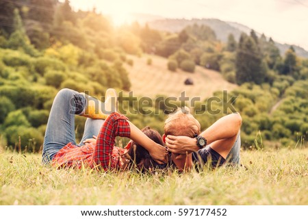 Couple in love rest on green hill in country side