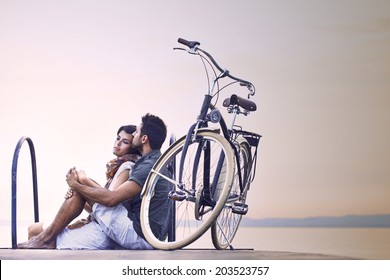 Couple in love resting on a boardwalk with a bike at the lake - Powered by Shutterstock