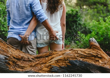 Couple in love seen from behind holding each other and touching their butt.
