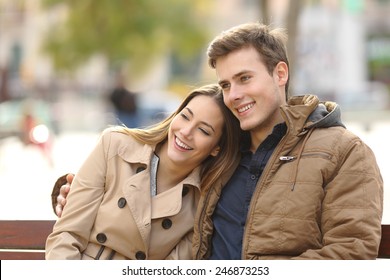 Couple in love sitting in a bench hugging in an urban park in winter
