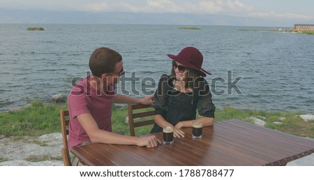 Couple in love sitting by the marina near the sea. Admire the scenery, hug, kiss, talk to each other and have fun