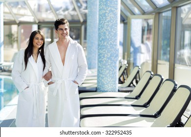 Couple in love standing next to a  pool in a  robe and relaxing
