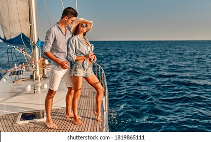 Couple In Love Standing On Yacht Deck While Sailing In The Sea. Handsome Man And Beautiful Woman Having Romantic Date. Luxury Travel Concept.