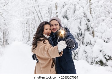 Couple Love Story in Snow Forest Kissing and Holding Sparklers. Couple in Winter Nature. Couple Celebrating - Powered by Shutterstock