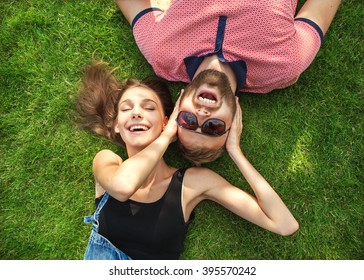 couple in love in sunglasses lying on the grass and laugh