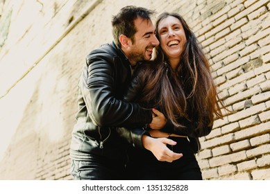 Couple In Love Tickling And Laughing Hard During A Casual Walk Through The City.