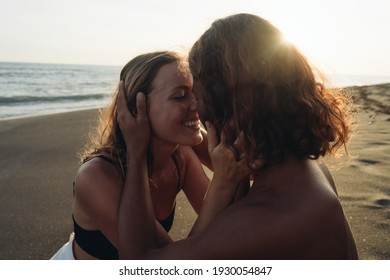 The couple in love touches each other's noses and smile with happiness against the backdrop of sand and ocean. High quality photo