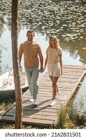 Couple In Love Walking Along A Wooden Jetty