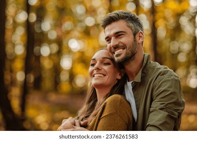 Couple in love walking in the woods while holding hands and smiling, feeling in love, smiling and laughing together - Powered by Shutterstock