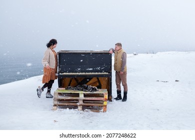 A couple in love walks on the shore of the winter sea, a man and a woman are frozen, it is snowing, girl and a guy are standing near the piano