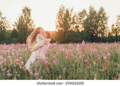 A Couple In Love Walks Through A Flower Meadow. Love And Spring Blooming. A Man Embraces A Woman