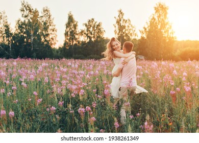 A Couple In Love Walks Through A Flower Meadow. Love And Spring Blooming. A Man Embraces A Woman