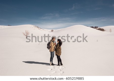 Couple in love walks in winter in the snow. Man and woman traveling. Couple in love in the mountains. Travelers in the mountains. Winter walk. Winter adventures. Winter walk. Couple in love hot tea