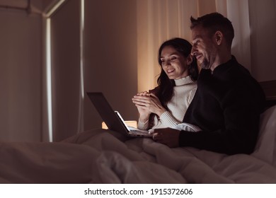 Couple love watching movie together on the bed. Happy couple enjoying and smiling on winter season.