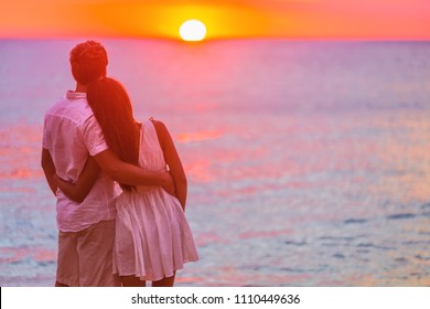 Couple In Love Watching Sunset Together On Beach Travel Summer Holidays. People Silhouette From Behing Standing Enjoying View Of Ocean On Tropical Destination Vacation.