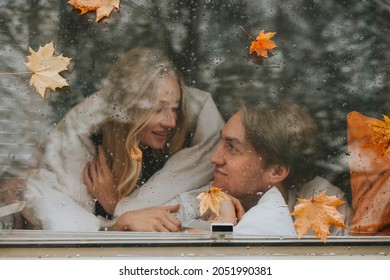 Couple In Love From Window With Rain Drops And Autumn Leaves Having Fun Together, Young Man And Woman Newlyweds Hugging On Bed In Trailer Mobile Home Or Recreational Vehicle During Family Local Travel