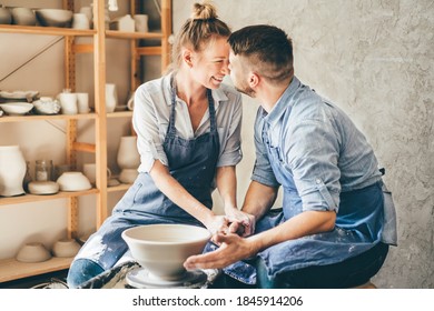 Couple in love working together on potter wheel in craft studio workshop. - Powered by Shutterstock