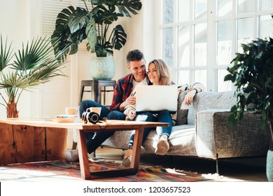 Couple In Love. Young Family Watching TV Series Using Laptop In Cozy Loft Apartment