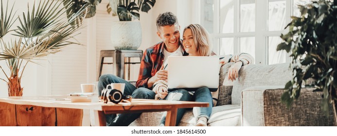 Couple In Love. Young Family Watching TV Series Using Laptop In Cozy Loft Apartment. Wide Screen, Panoramic