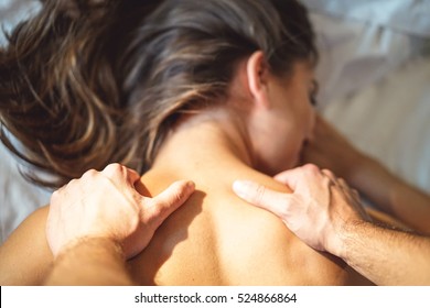 Couple and lovely moments in the bed - Close up of boyfriend giving massage for his beautiful girlfriend relaxing in a bed whit white sheets - Focus on hand