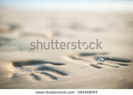 Couple of lovers at a beautiful sunset over the ocean. Couple on a romantic vacation. Imprint pair of hands in the sand, wedding ring