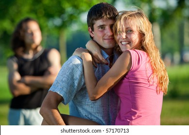 A couple of lovers embrace in a park on the background of the third young man