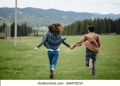 Couple Of Lovers Holding Hands And Running Away In Mountains. Woman And Man In Love Walking Outdoors. 