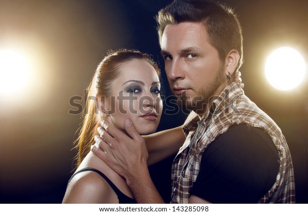 Couple of lovers.\
Couple of independent steep young people who love each other on a\
black background with glowing lights (headlights of cars). Both are\
looking at the camera