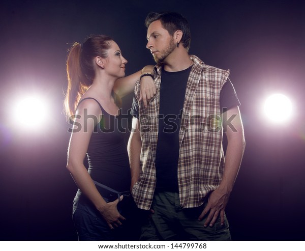 Couple of lovers. Couple of independent steep young\
people who love each other on a black background with glowing\
lights (headlights of\
cars)
