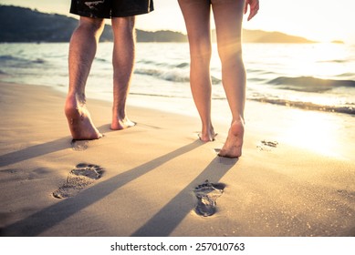 Couple of lovers walking on the each at sunset - Foot prints on the beach