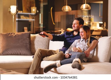 A Couple Of Lovers Watch Television Embraced On The Sofa In The New House And Watch A Movie Together. Concept Of: Leisure, Relax, Tv.